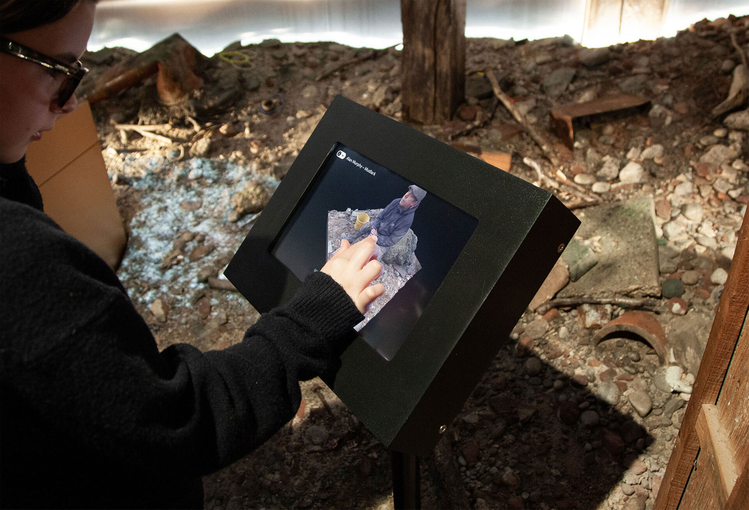 A girl using a touchscreen interactive at the London Museum Secrets of the Thames Exhibition. The screen shows a 3d capture of the Thames foreshore.